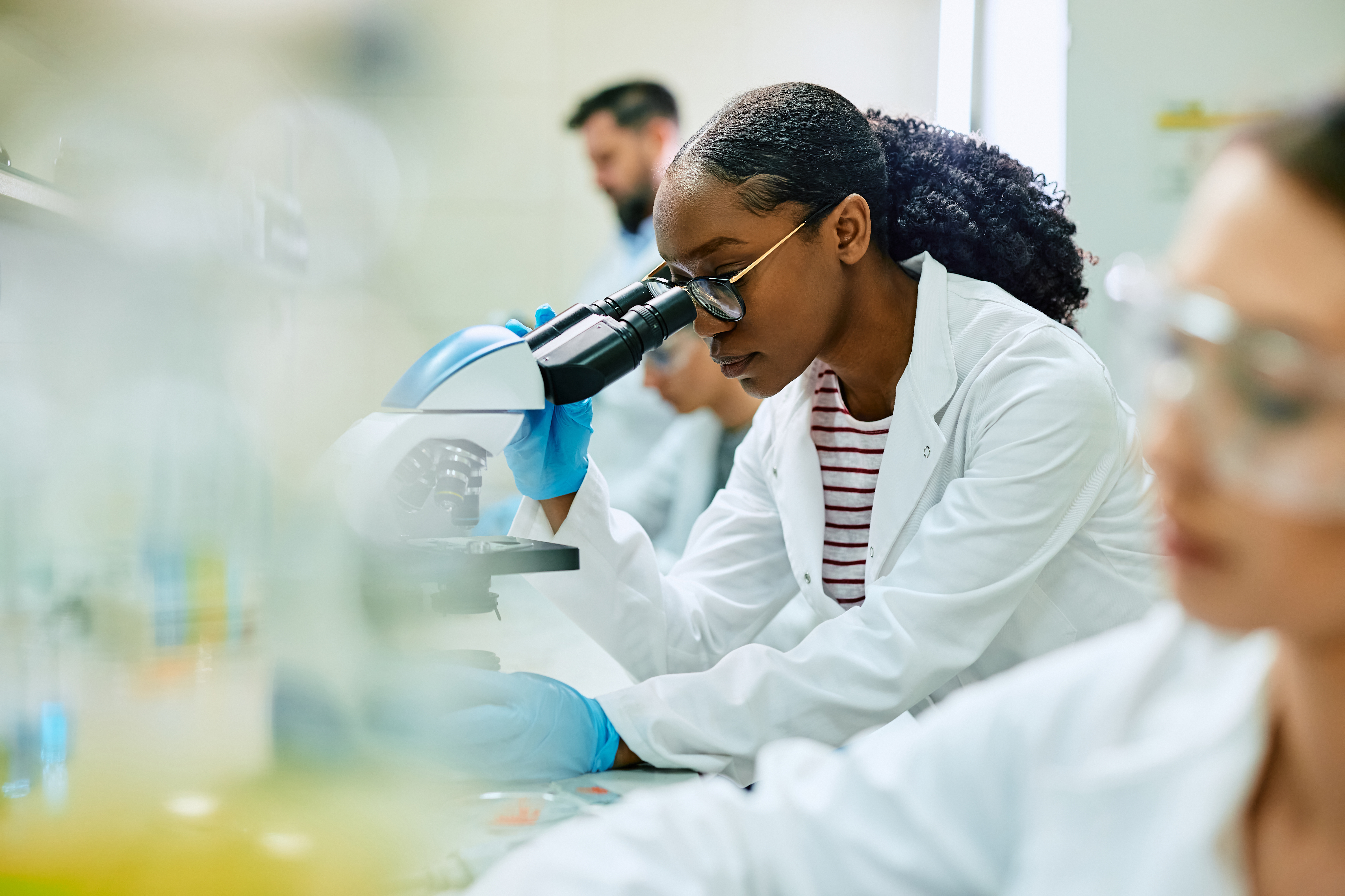 scientist looking through microscope while working in laboratory