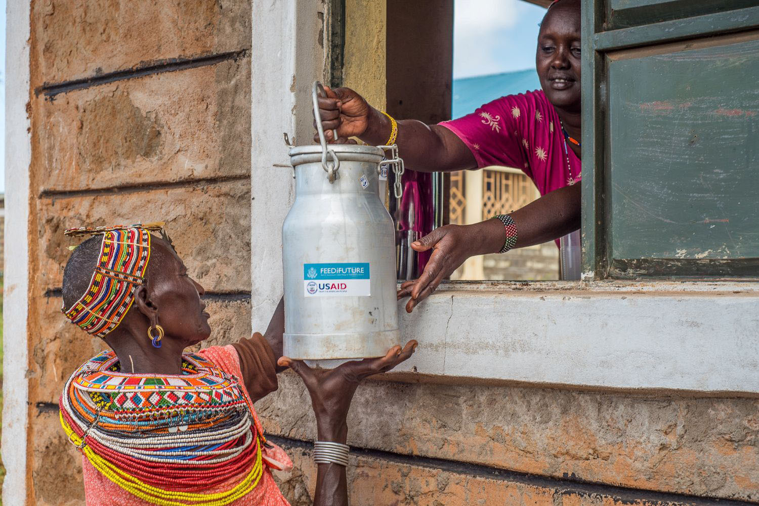 Two community members exchanging a USAID branded jug in Africa