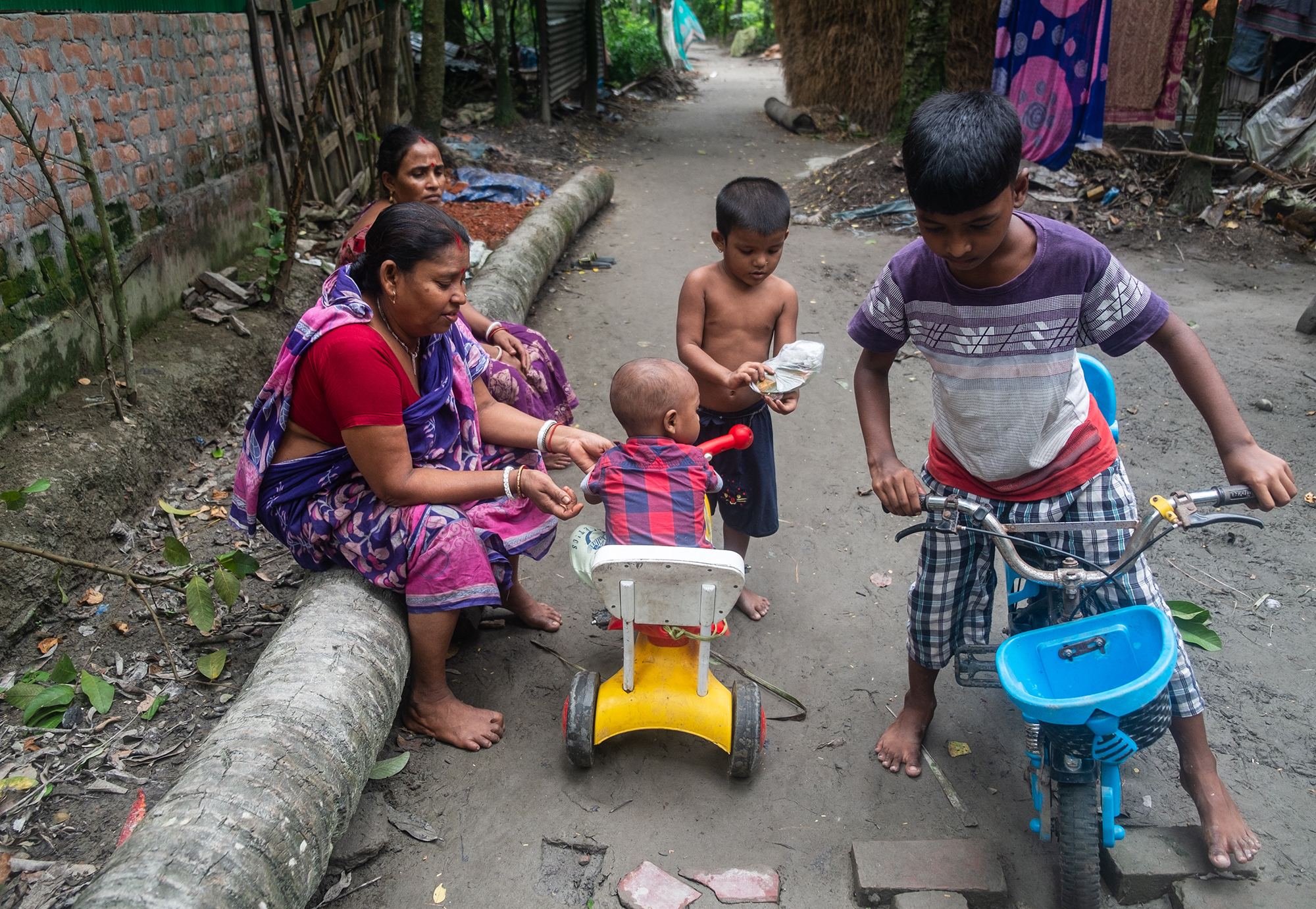 Two women and three children under the age of 10 play outside with toys