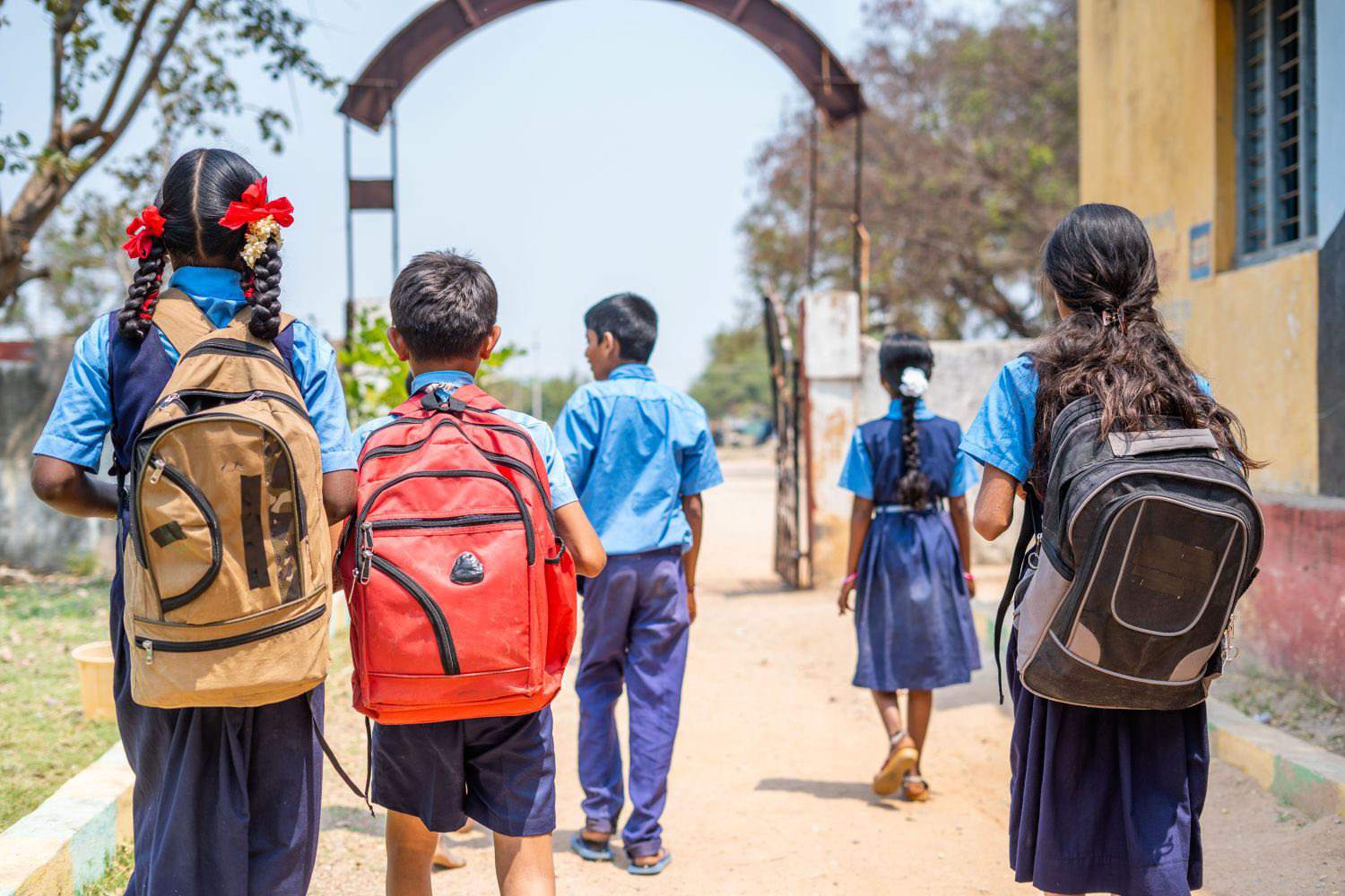 Back view shot of group of children in unifrom going home from school after classes