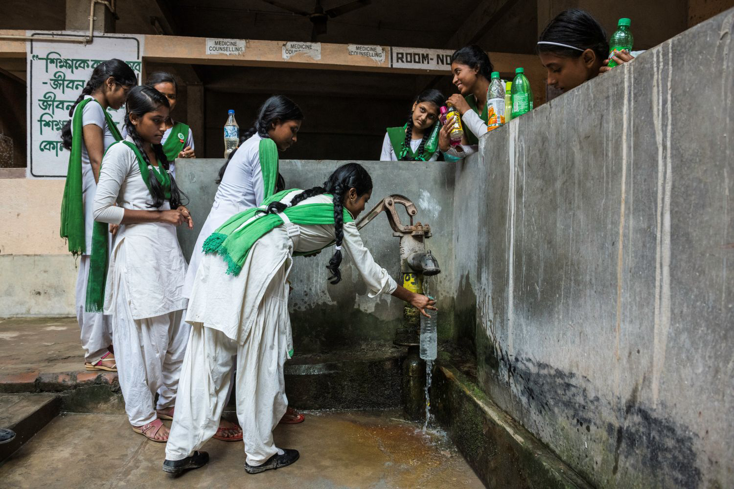 Image of students drinking water from a water pump in West Bengal India