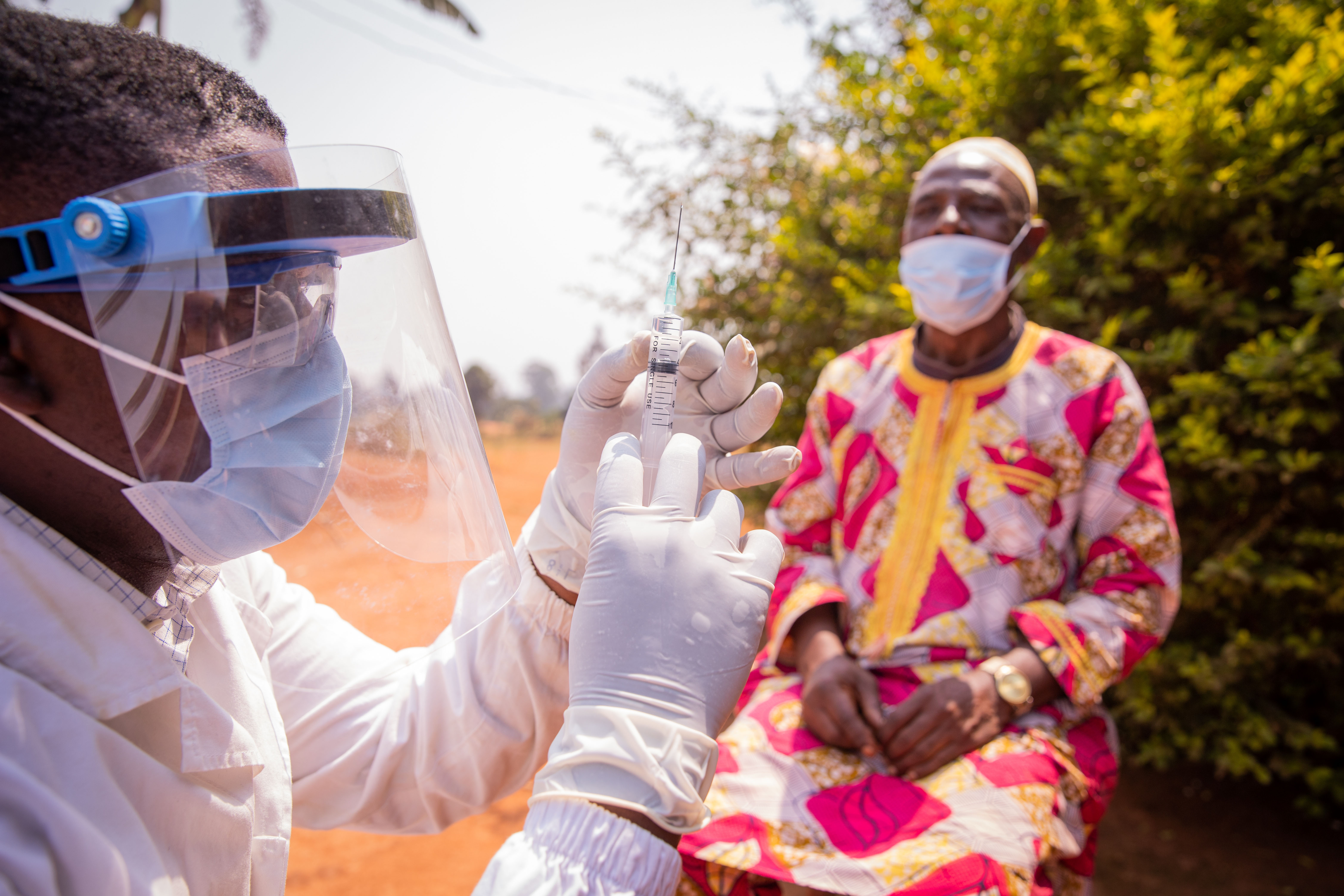 An African doctor prepares a syringe to inject the vaccine into an elderly patient. Concept of vaccination from Covid-19 in Africa