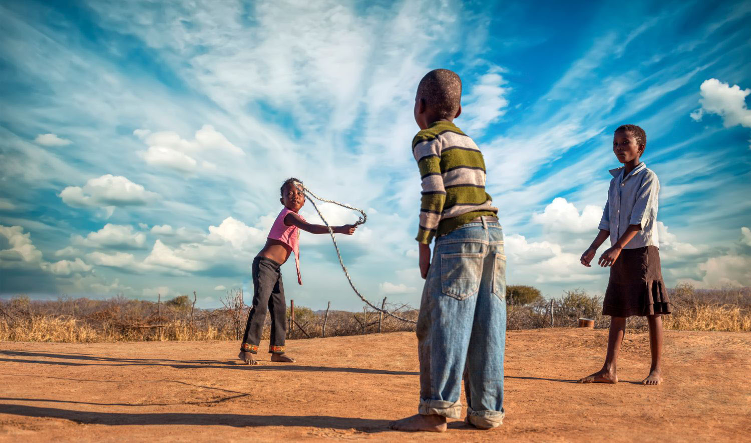 Three children skipping rope in the village