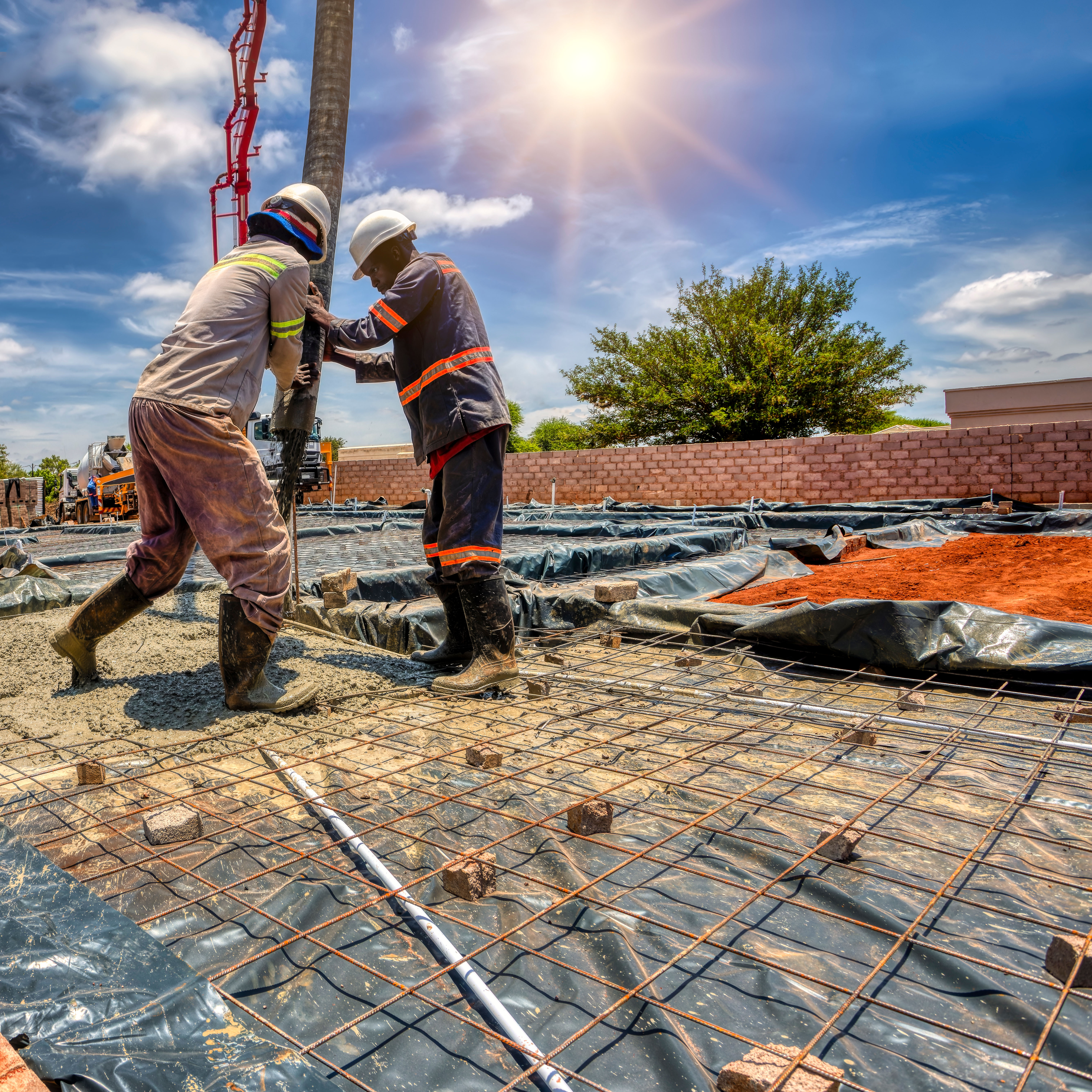 Construction workers using a boom concrete pump to fill the foundation of a building