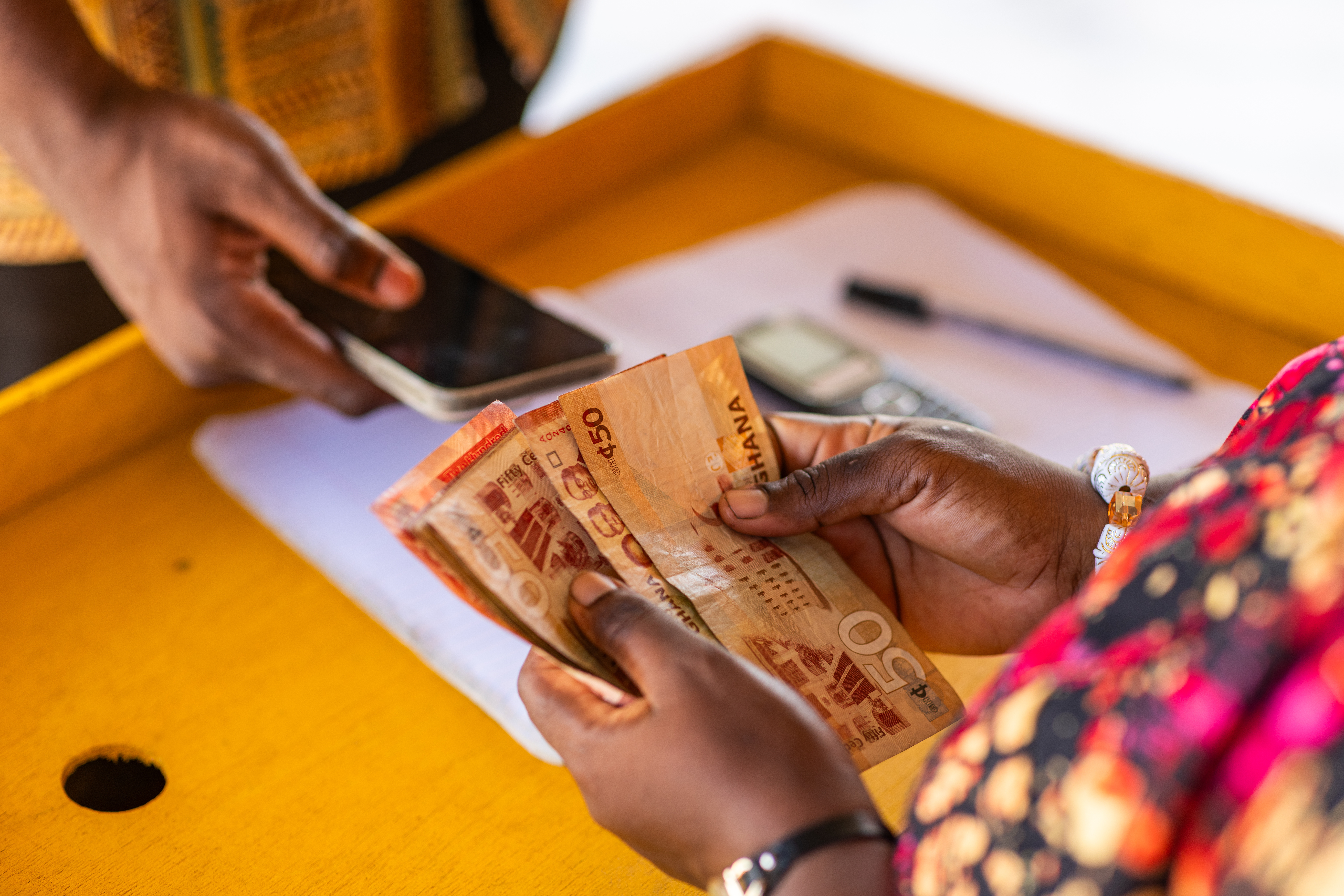 Mobile money (MoMo) agent handing cash to a customer after a withdrawal transaction in Ghana
