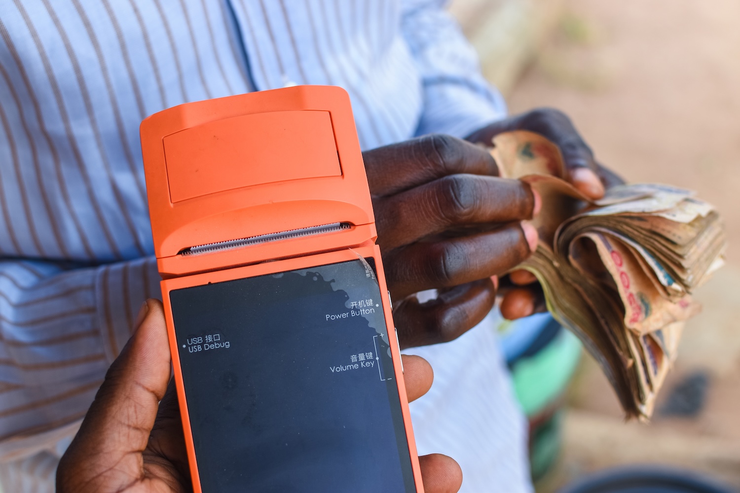  hands counting money while another hand is holding a digital point of sales machine