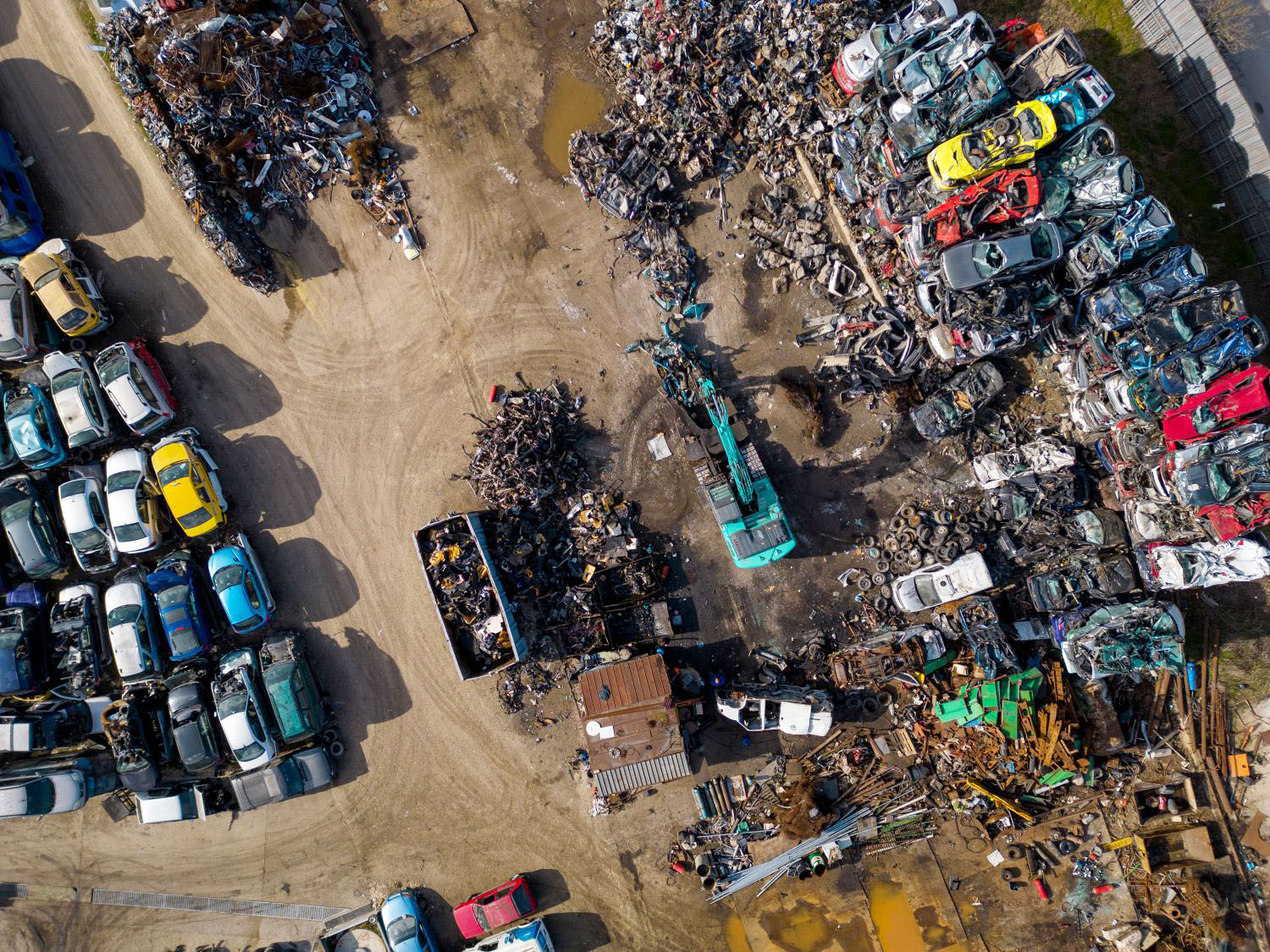 aerial view of a car dump, where a machine is seen separating old cars into scrap