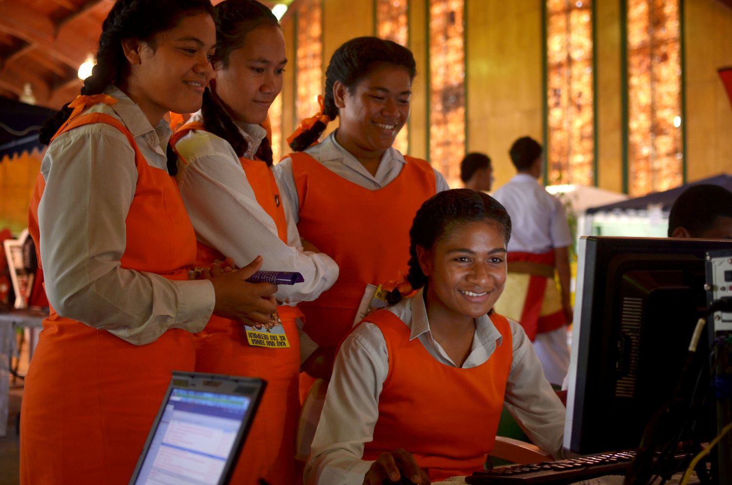 For young women in school uniform staring at a computer. 
