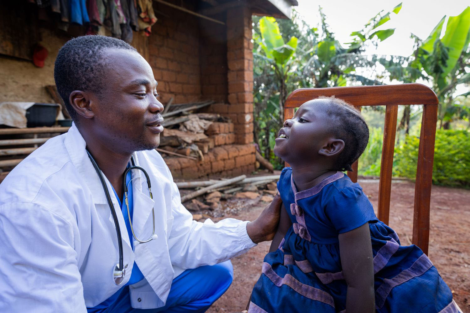 African doctor talking to child during a visit in a remote area