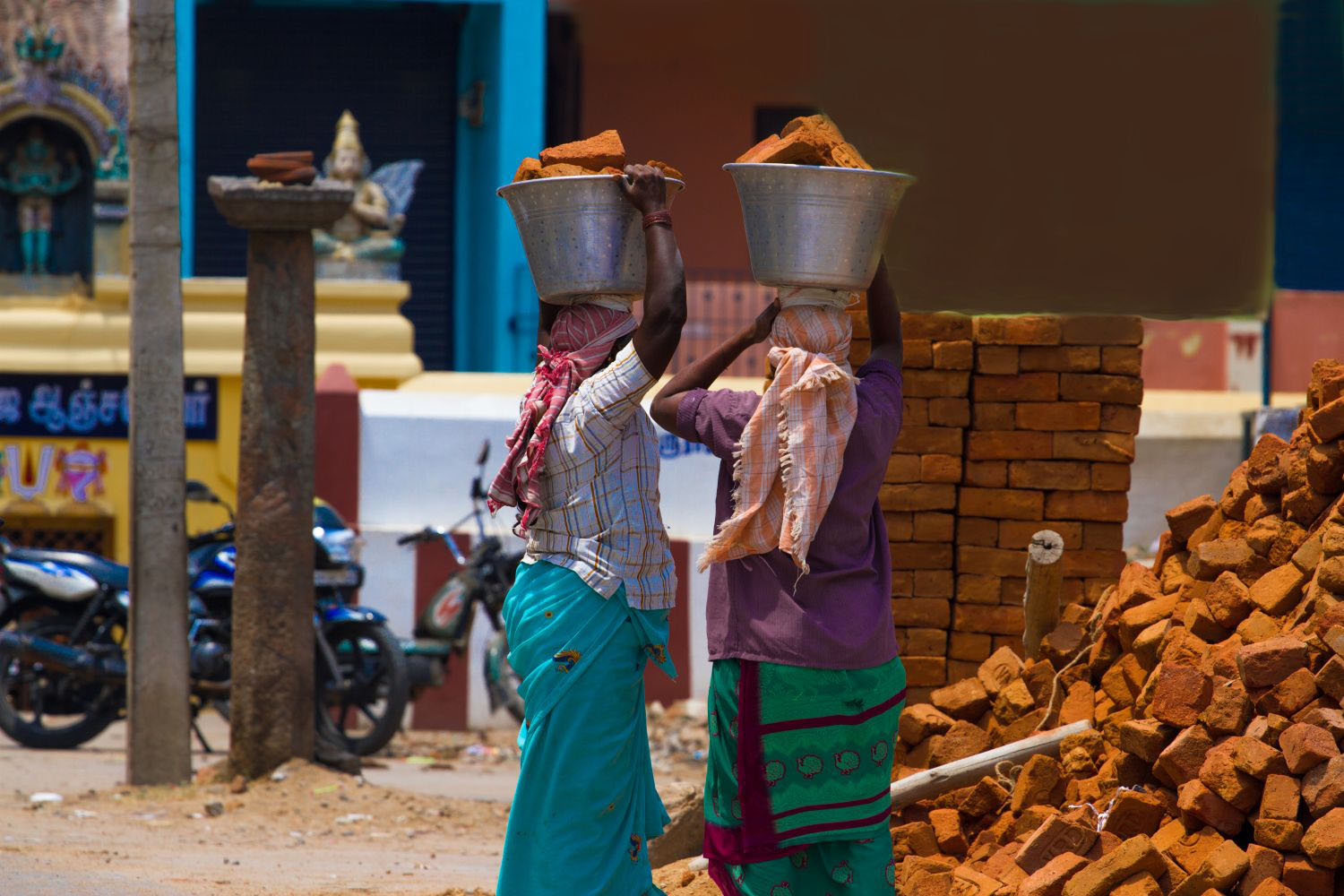 Women carrying heavy bricks of clay on their heads.