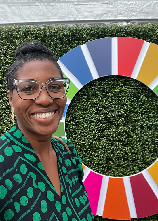 Kehinde Ajayi, Director of Gender Equality and Inclusion, standing outside in front of the UNGA81 signage