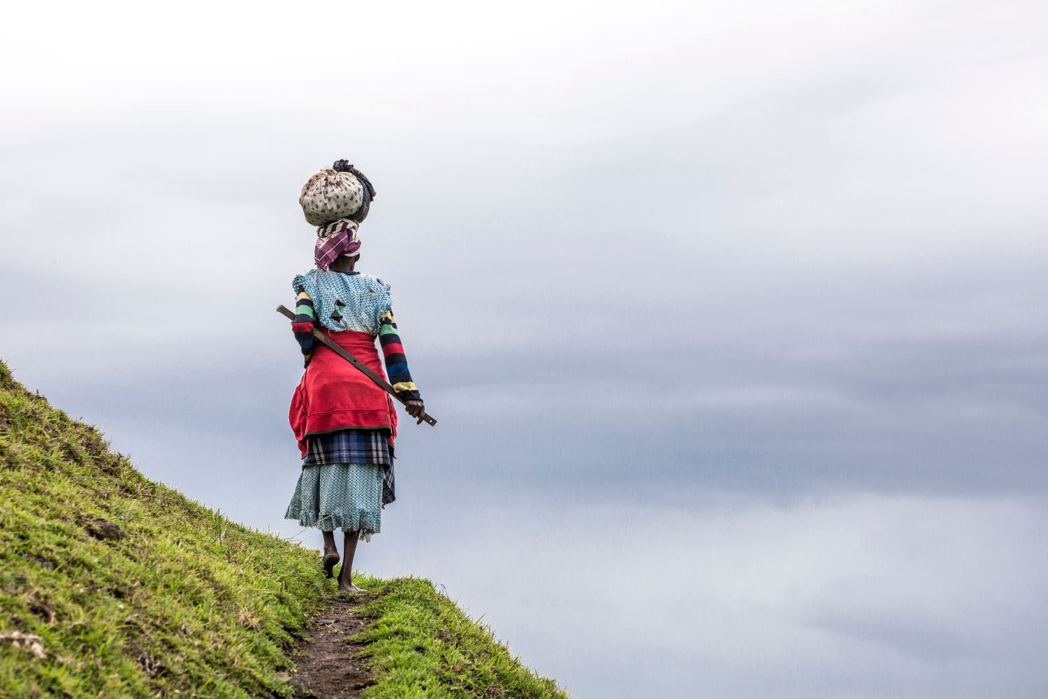 African woman carries a load on her head in the hills of South Africa