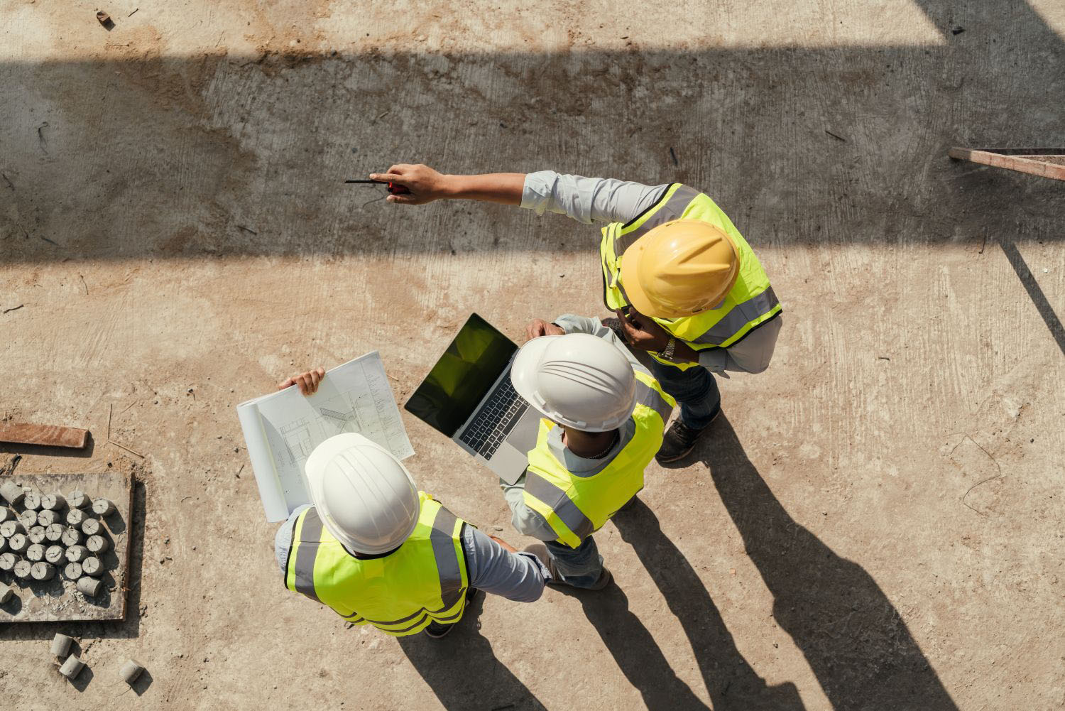 Construction worker conducting a building inspection using a computer and blueprint working at a construction site.