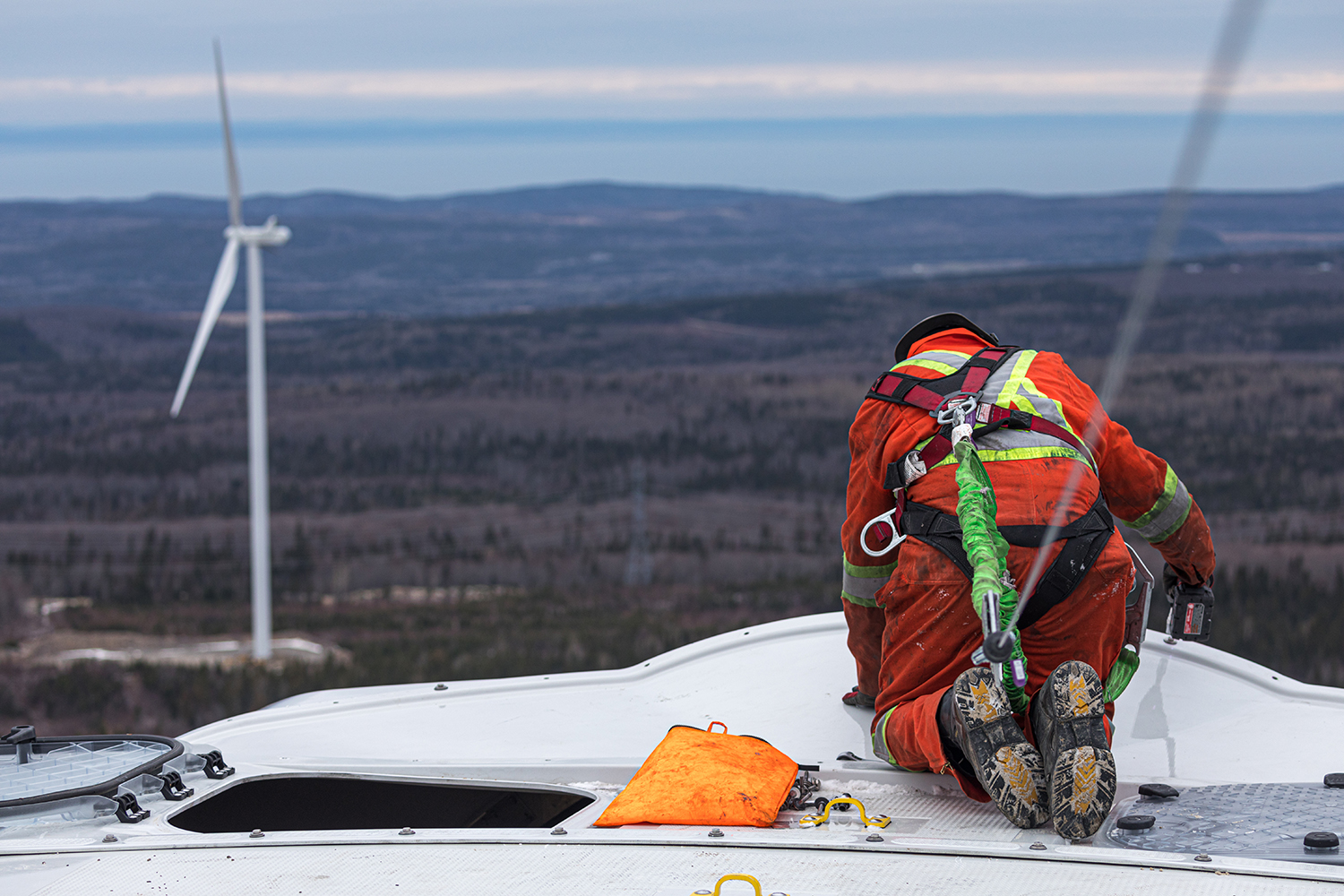 A worker in security harness fixing bolts on a wind turbine