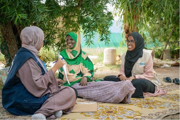 WFP staff sit with a woman. WFP/Arete/Utaama Mahamud