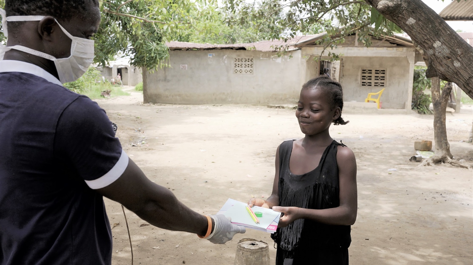 A student in Liberia receives her learning material to continue studying at home