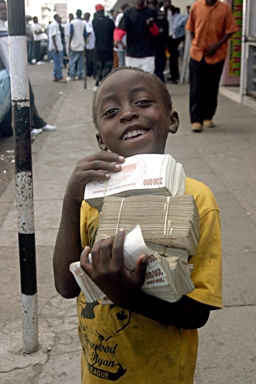 child holding stacks of Zimbabwean dollars