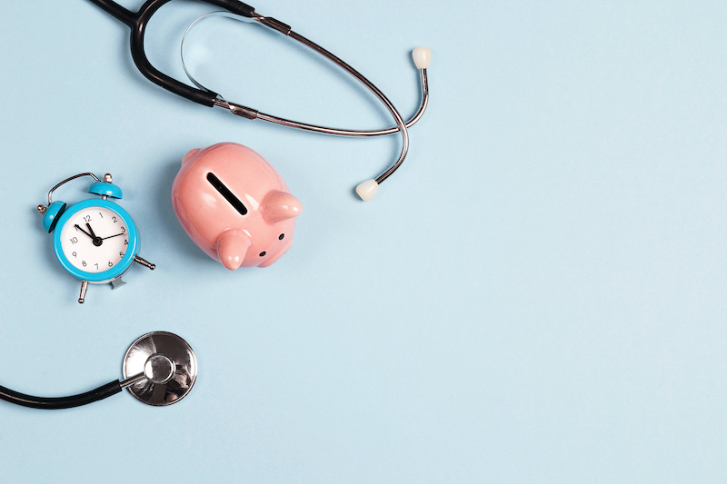 A piggy bank and stethoscope on a blue background